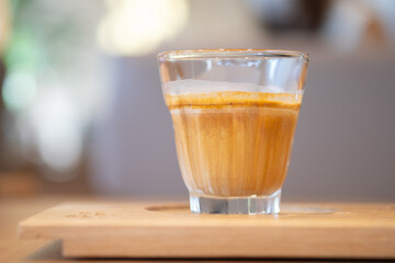 A glass of espresso shot over cold fresh milk create gradient layer called dirty coffee