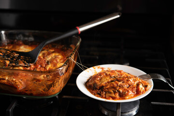 Baked Eggplant Parmagiana From Oven With Red Sauce and Cheese Being Served on White Plate