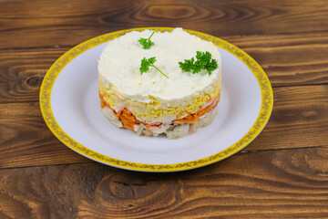Tasty layered salad with chicken, carrot, eggs, cheese and mayonnaise on wooden table