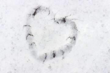 Heart shape drawn on snow close-up, winter background