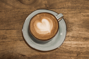 Obraz na płótnie Canvas Beautiful cup of coffee with a heart shape on a wooden background. Place for your text. Valentine's day concept. Selective focus.