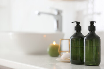 Green soap dispensers on countertop near sink in bathroom. Space for text