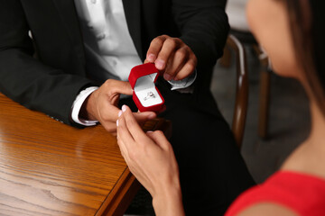 Man with engagement ring making proposal to his girlfriend at table, closeup