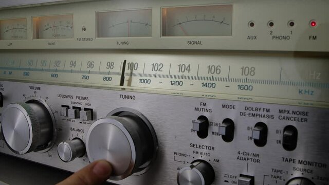 Vintage radio receiver and amplifier with fm scale. Male hand tune analog radio frequency on scale of the retro receiver. Searching for stations on the old radio. Close up. Slow motion.