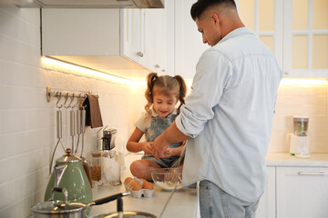 Little girl with her father cooking together in modern kitchen