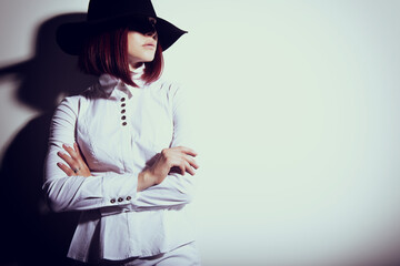 Mysterious fashion young woman in black hat and white shirt, copy space where can the advertising message be written