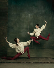 Flying. Two young female ballet dancers like duelists with swords on dark green background....