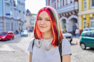 Fashionable beautiful girl teenager in wireless headphones with bright dyed colored hairstyle
