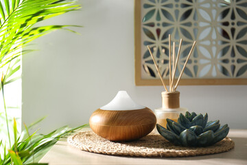 Aroma oil diffuser and reed air freshener on table in room