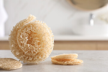 Natural loofah sponges on table in bathroom. Space for text
