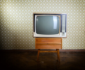 Retro tv on wooden case in room with vintage wallper and parquet