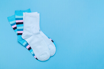 two pairs of multicolored new socks stacked on a blue background. top view.