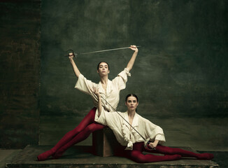 Lovely. Two young female ballet dancers like duelists with swords on dark green background....