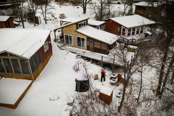 Man building a fire outside his little cabin in winter.