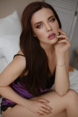 Obraz na płótnie Canvas Magnificent young woman with perfect makeup and beautiful long healthy hair in satin underwear posing on the bed. Beautiful model girl with pink full lips and deep seductive eyes