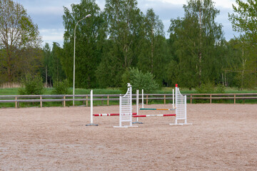Wooden barriers, equestrian obstacles, barriers on the sand ground for jumping horses and riders at riding school