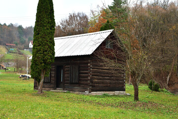 Obraz premium Old wooden house on a meadow near an agricultural field