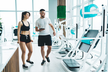 Coach with woman choosing exercise machine