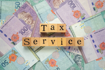 Text TAX SERVICE on wooden cubes with a bundle of the banknote. Flat lay view concept.