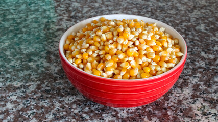 Corn kernels in a bowl on marble background.