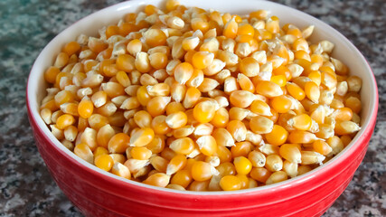 Corn kernels in a bowl on marble background.
