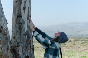 The girl stretched her arms up and put her palms on the tree looking up
