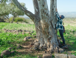 The girl stretched her arms up and put her palms on the tree looking up