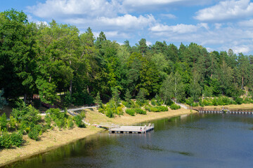 Bank of the Ogre river in the town of Ogre. The embankment is overgrown with forest and a pantone bridge across the river. Countryside and nature of Latvia.