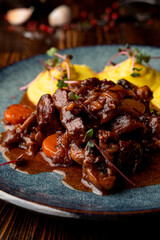 Close up of austrian goulash with spicy tomato sauce, with mashed potato as a side dish on a dark wooden table