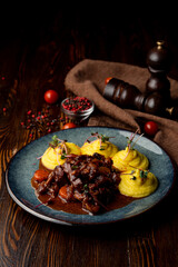 Beef with spicy gravy and mashed potato as a side dish on a dark wooden table