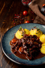Close up of austrian goulash with spicy tomato sauce, with mashed potato as a side dish on a dark wooden table