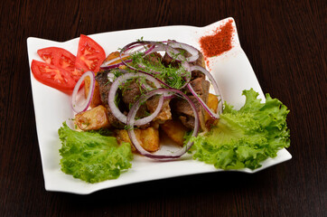 fried pieces of potato and beef sprinkled with onions and dill with salad, spices and tomatoes