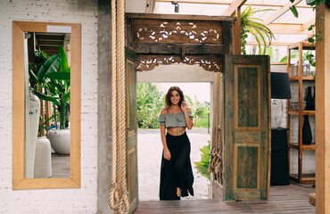 Joyful ethnic woman standing on doorstep