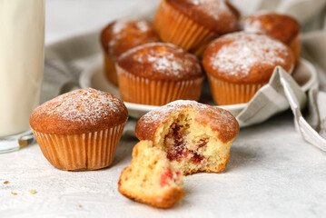 Macro photo of few of homemade muffins with filling and fragment of glass of  milk on a white table