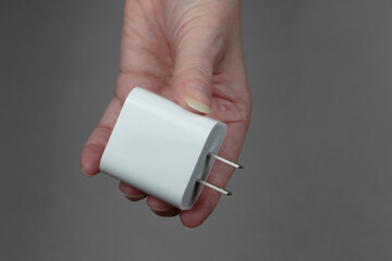 close-up shot of a USB-C 20 watt power adaptor showing the pronged plug side being held by a hand