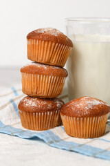 A stack of homemade muffins and a glass of  milk close up on a white table
