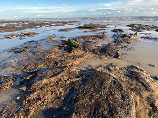 Pett Level Beach at Sunset. With pool of sea ocean water and rocks in foreground. Winchelsea Beach meets the cliffs a petrified forest visible at low tide, on the South coast of England East Sussex UK