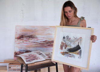 Modern art and lifestyle. Female artist showing her work in the studio. Casual portrait of young...