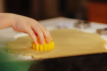 the child cuts out cookies from the dough with a mold