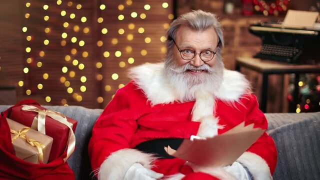 Male Santa Claus smiling read wish list with surprised face expression. Medium shot on RED camera