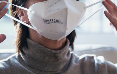 Corona Schutzmaske / FFP2 Atemschutzmaske / Frau / Altenpflege / Maske aufsetzen
