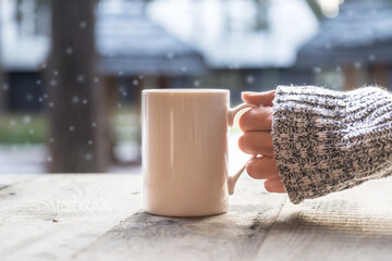 Woman hand holding coffee cup, mug on old wooden table in winter day