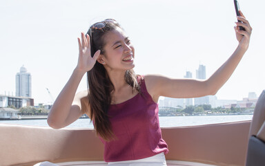 Asian woman taking selfie while travelling and sitting on boat