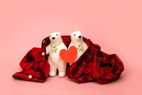 two polar bears toys with red heart wrapped in plaid shirt on pink background. Concept for dating, valentines day, care