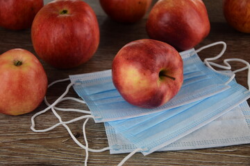 Jabłka i maseczki ochronne na drewnianym tle