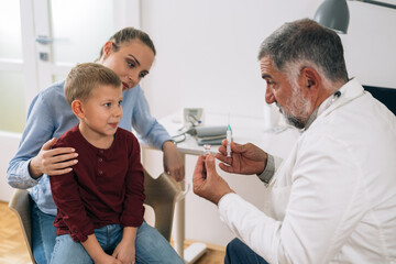 mother and her child visiting pediatrician. boy receives vaccine