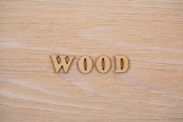Wood word written in wooden alphabet letters on wooden background. Text on the table for design or concept.