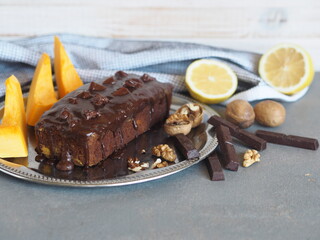 Festive homemade chocolate pumpkin long rectangular cupcake glazed with chocolate. Wooden table.