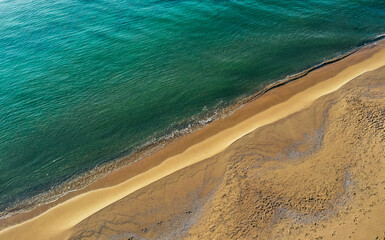 Sea coastline, above view, beach background. Ocean surface seashore, seaweed on the water. Footprints on the sand.