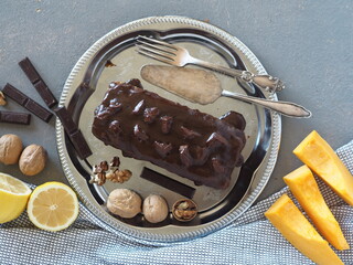 Festive homemade chocolate pumpkin long rectangular cupcake glazed with chocolate. Wooden table.